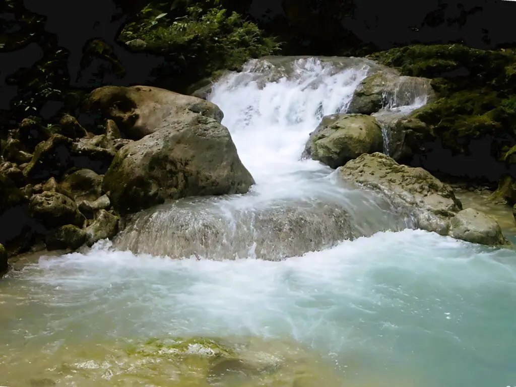A small waterfall cascading over rocks into a clear pool.