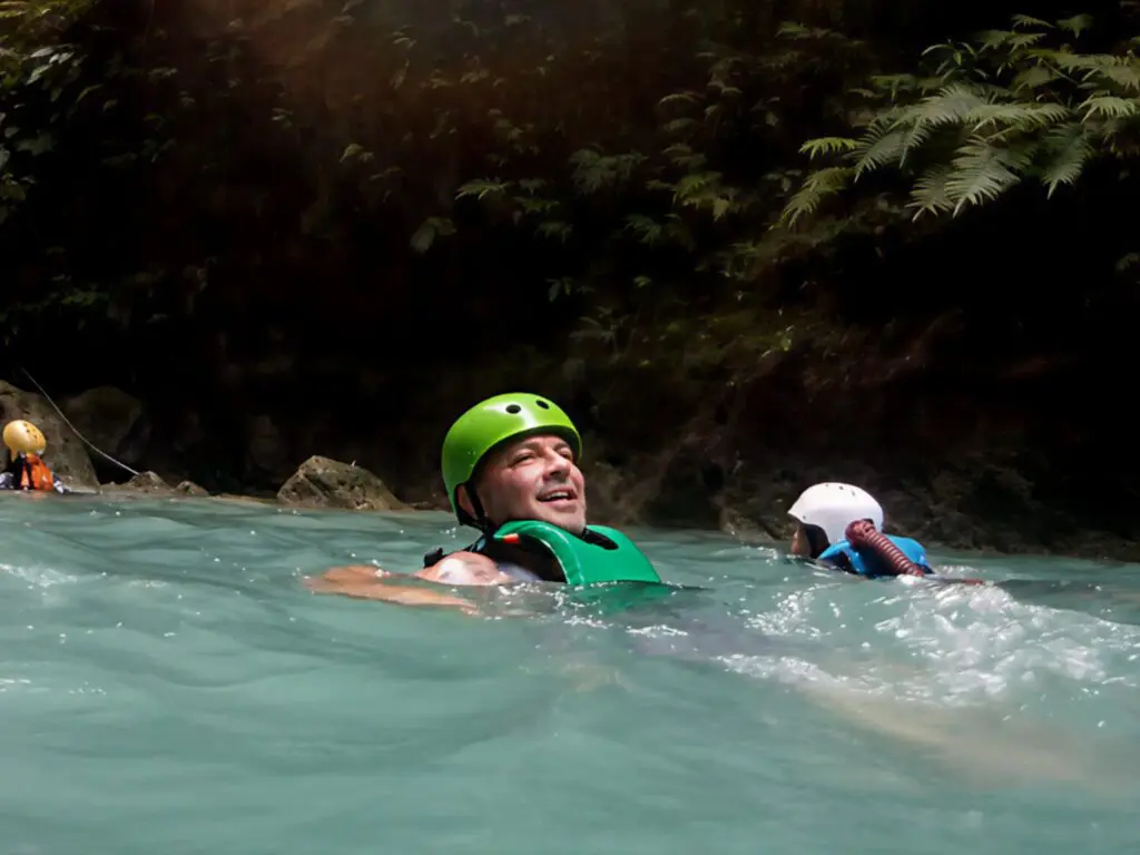 Person in green helmet enjoying whitewater rafting.