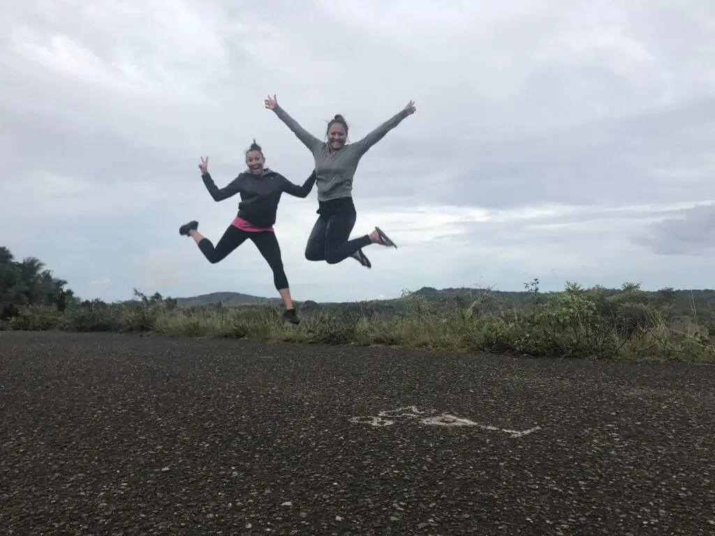 Two people joyfully jumping outdoors on a cloudy day.
