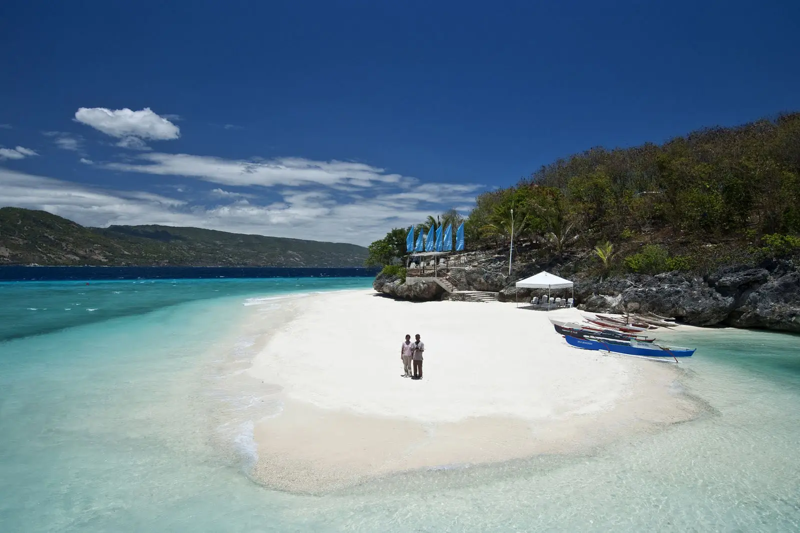 Couple standing on a pristine white sand beach with turquoise waters.