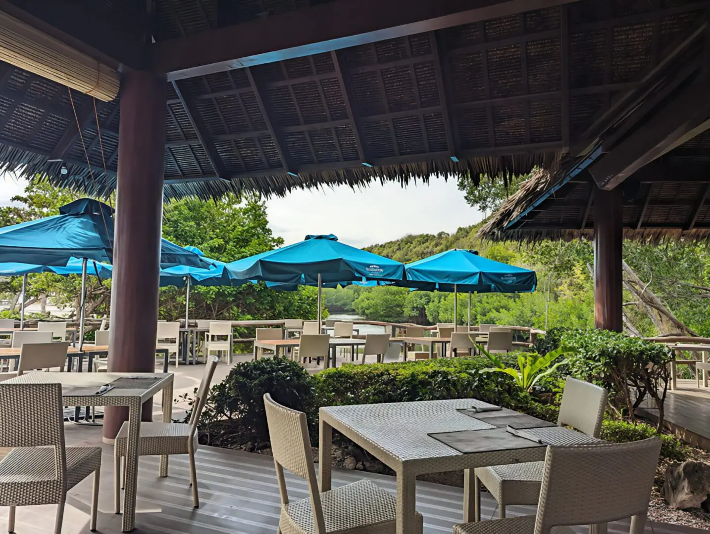 Outdoor dining area with wooden tables and blue umbrellas.
