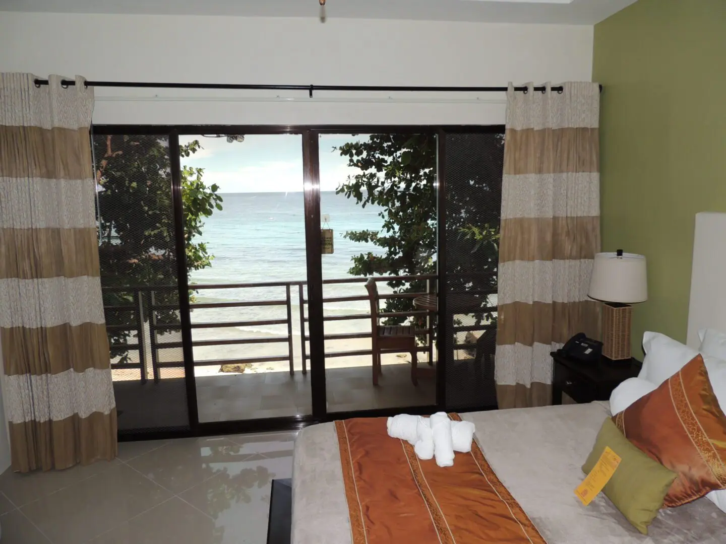 Cozy room with a balcony overlooking the ocean and trees.