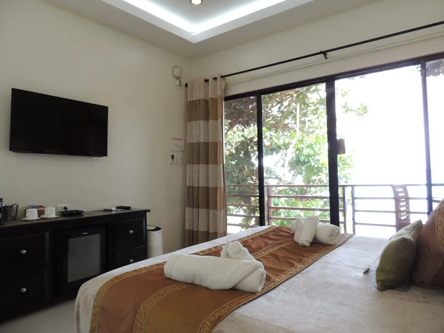 Bright and cozy bedroom with a large window and neatly arranged towels.