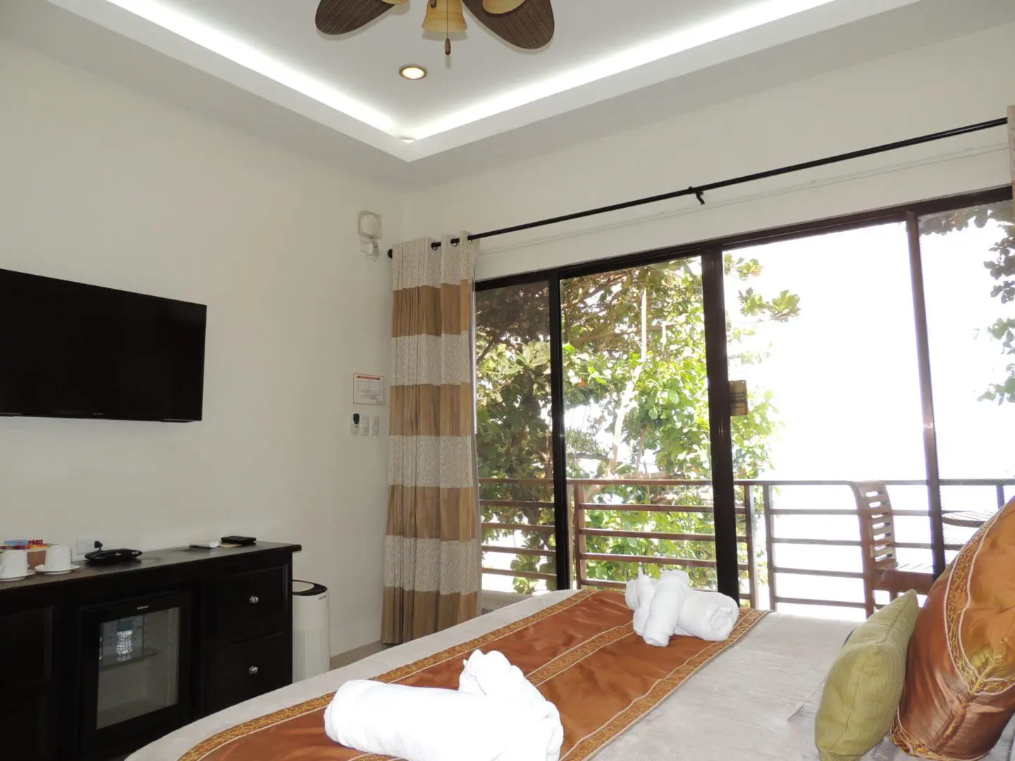 Bright bedroom with a balcony view and neatly arranged towels on bed.