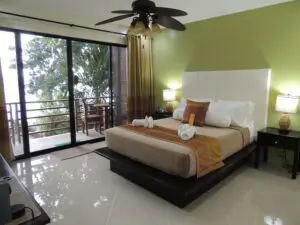 Modern bedroom with green accent wall and outdoor balcony view.