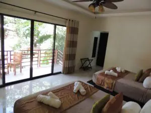 Cozy bedroom with twin beds and a balcony overlooking greenery.