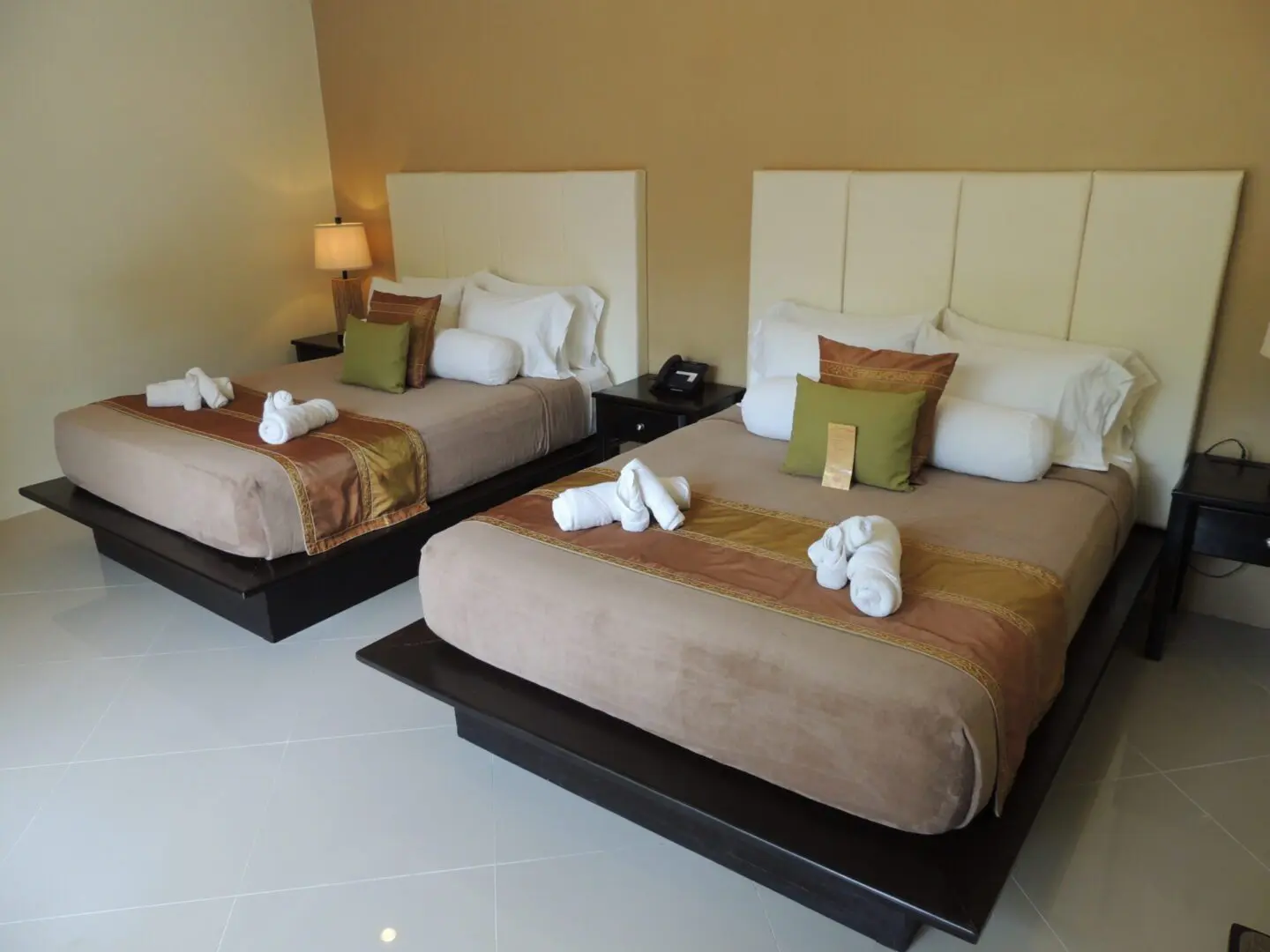 Two neatly made beds with folded towel swans in a modern hotel room.