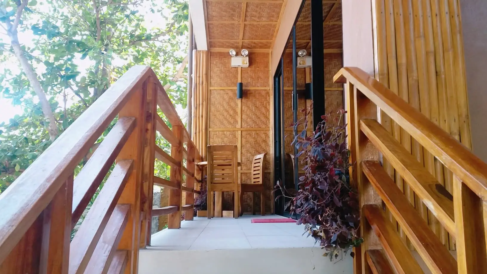 Cozy outdoor porch with wooden railing and chairs.